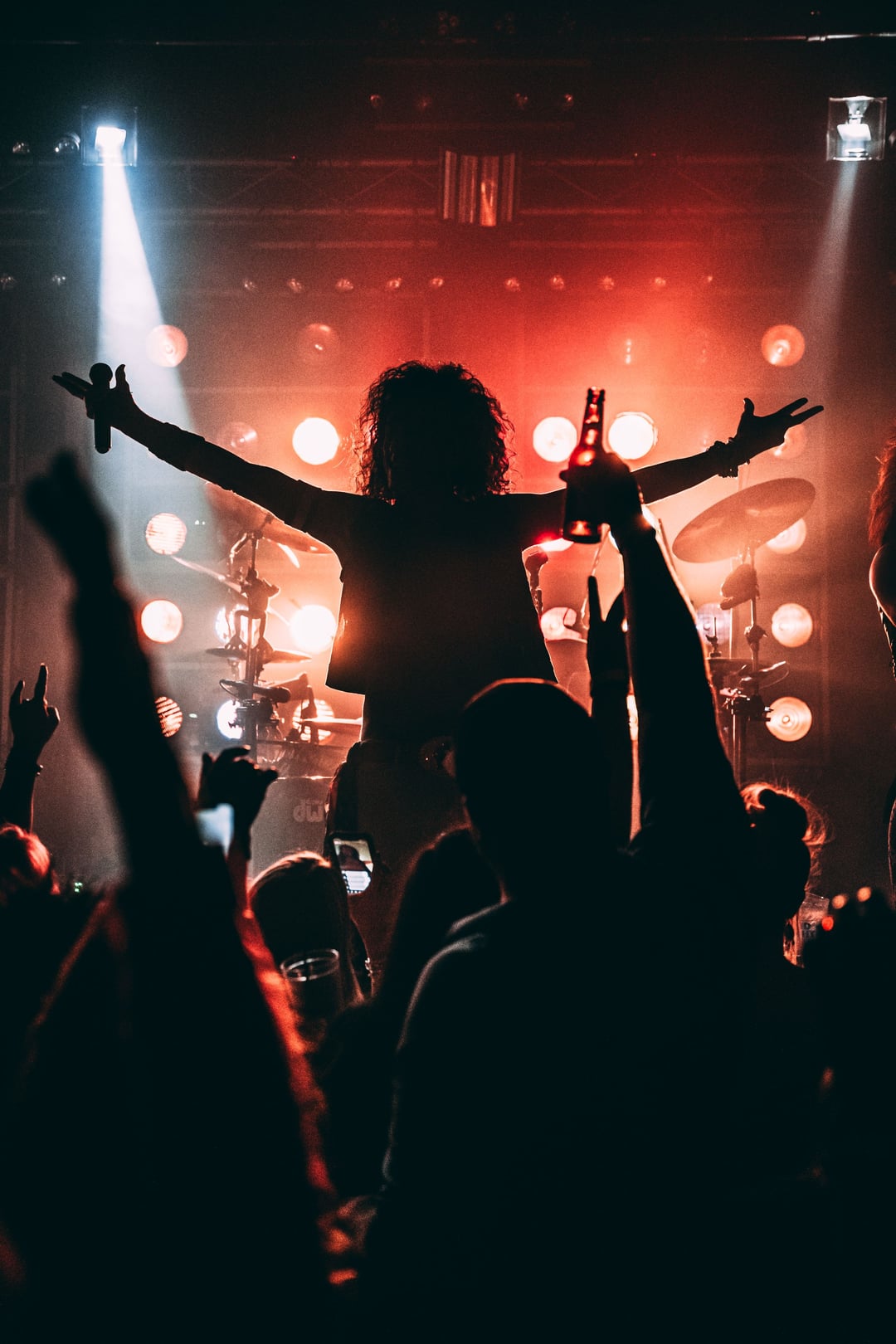 A singer on stage with arms open wide to a crowd raising their hands
